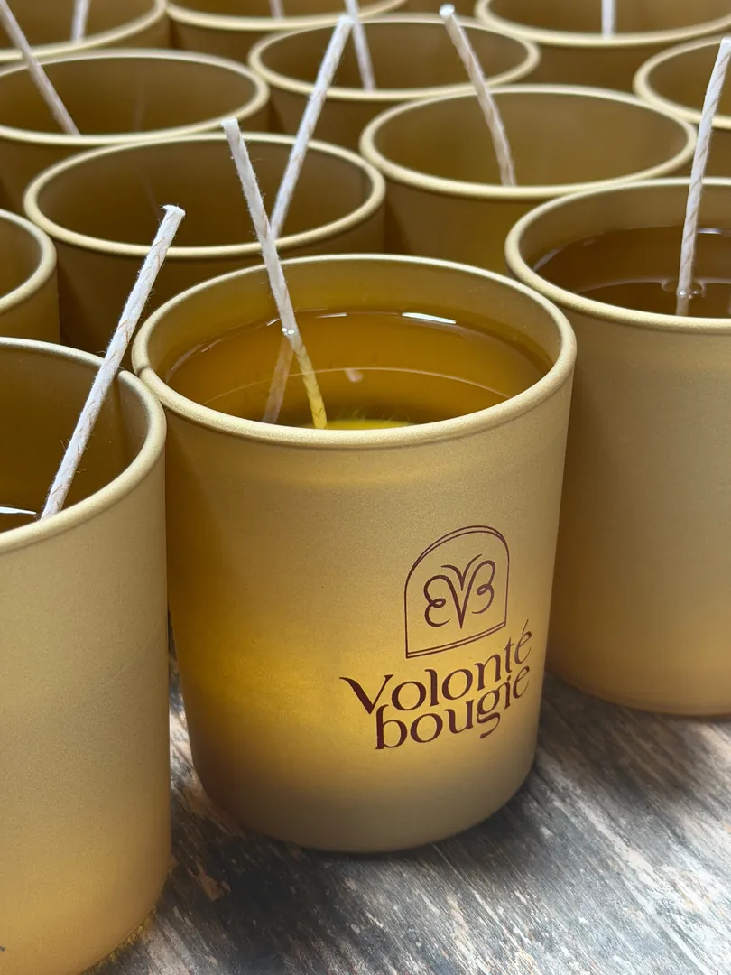 Vaso dorado mate de La Befana Noël con la cera todavía líquida, de color ámbar, y la mecha en el centro